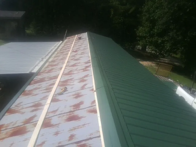 Old rusted panels beside newly installed green metal roofing — Wind Damage Roof Repair by Roofing Brothers in Indian Rocks Beach